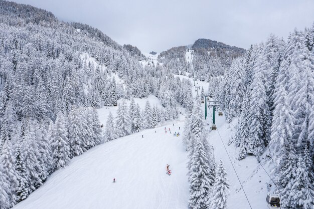 Foto aérea de uma pista de esqui em uma paisagem de neve sob a luz do sol