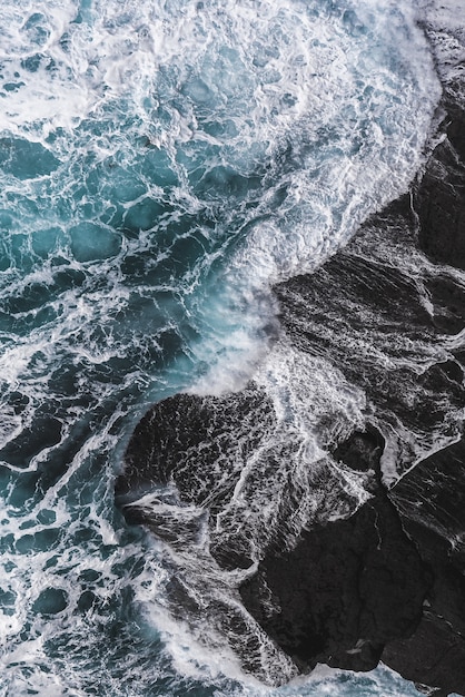 Foto aérea vertical das ondas do mar batendo nas rochas