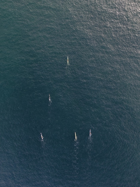 Foto aérea vertical de pessoas em barcos de caiaque remando em um oceano de águas límpidas e calmas