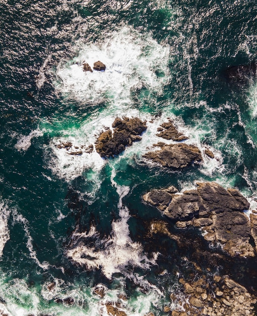 Foto aérea vertical de um mar com pedras rochosas