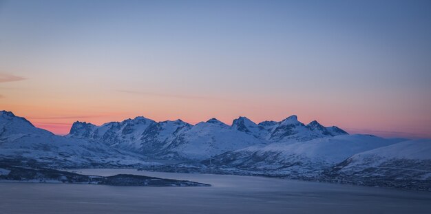 Foto ampla das montanhas cobertas de neve de tirar o fôlego capturada em Tromso, na Noruega