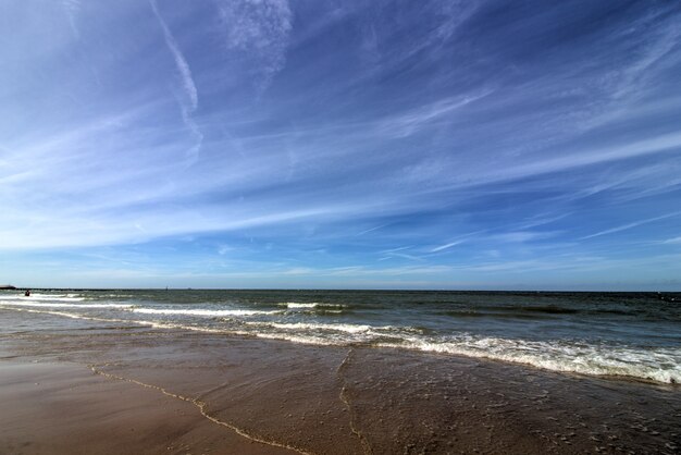 Foto ampla de uma praia de areia com céu azul claro