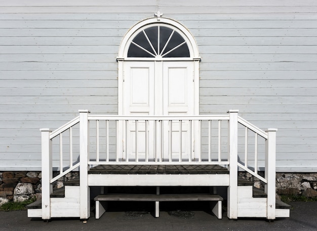 Foto aproximada da entrada de madeira branca e dos degraus de uma bela casa de madeira