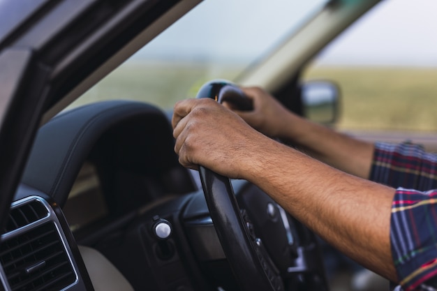 Foto aproximada das mãos de uma pessoa no volante de um carro moderno