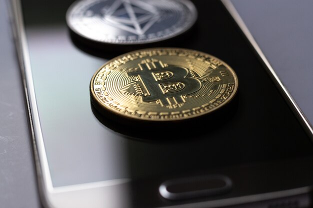 Foto aproximada de duas moedas colocadas em cima de um telefone celular