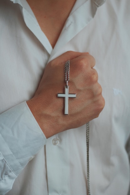 Foto grátis foto aproximada de um homem religioso segurando um colar de prata com uma cruz pendente