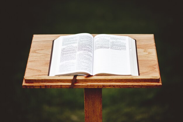 Foto aproximada de um suporte de discurso de madeira com um livro aberto