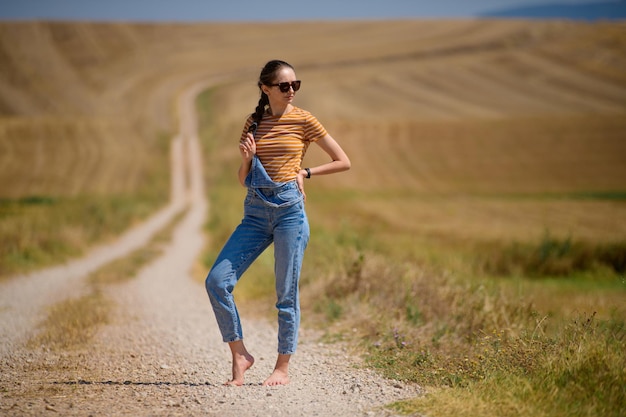 Foto aproximada de uma jovem mulher parada em um caminho no campo