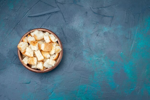 Foto colorida de lanche de bolachas em fatias de pão dentro de uma tigela marrom na mesa azul-escura