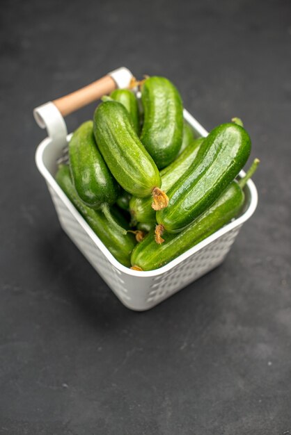 Foto colorida de pepinos verdes frescos dentro de uma cesta em um fundo escuro refeição de salada