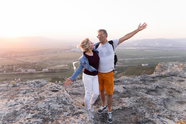 Foto completa casal viajando em um penhasco