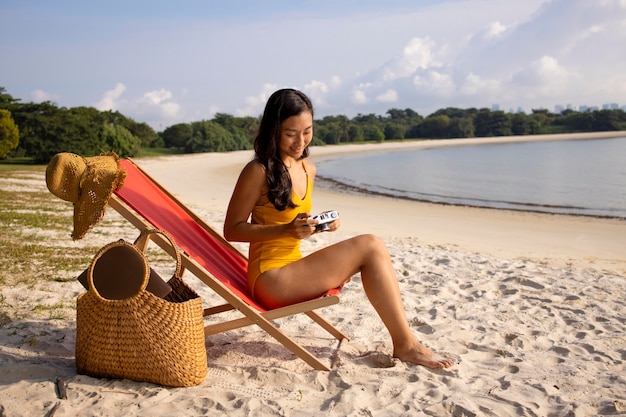 Foto completa de mulher na praia na cadeira