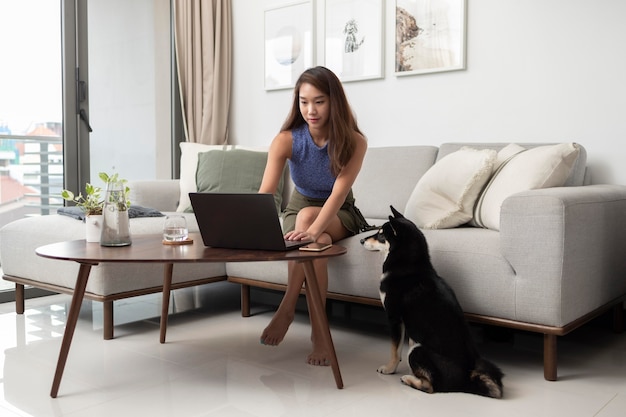 Foto completa de mulher trabalhando em um laptop com um cachorro