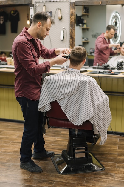 Foto completa do cabeleireiro dando um corte de cabelo