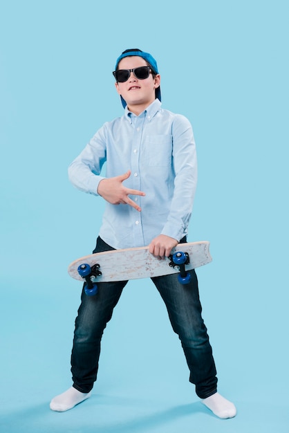 Foto completa do garoto moderno com óculos de sol e skate