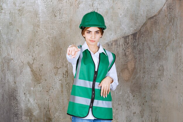 Foto grátis foto da bela arquiteta com capacete verde apontando