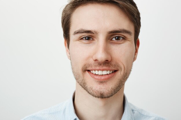 Foto da cabeça de um homem bonito e sorridente, parecendo esperançoso