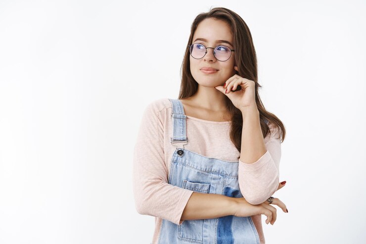 Foto grátis foto da cintura de uma mulher feminina bonita, criativa e otimista, de óculos, olhando para a esquerda com um sorriso de satisfação sonhadora tocando o queixo