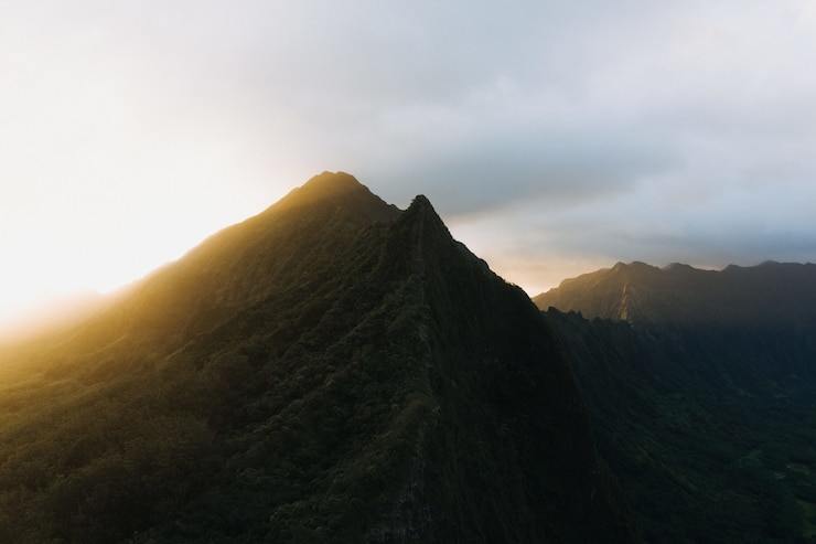 Foto grátis foto da silhueta de uma montanha íngreme com um pôr do sol em um céu azul nublado