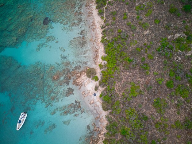 Foto da vista superior de um barco no mar azul perto da praia