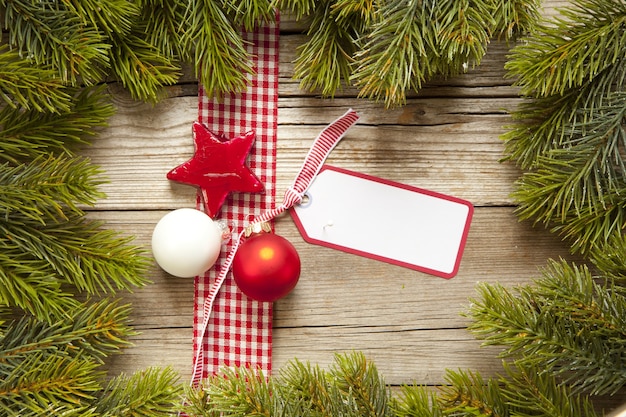 Foto da vista superior de um cartão de natal com uma fita e enfeites cercado por galhos de árvores de natal