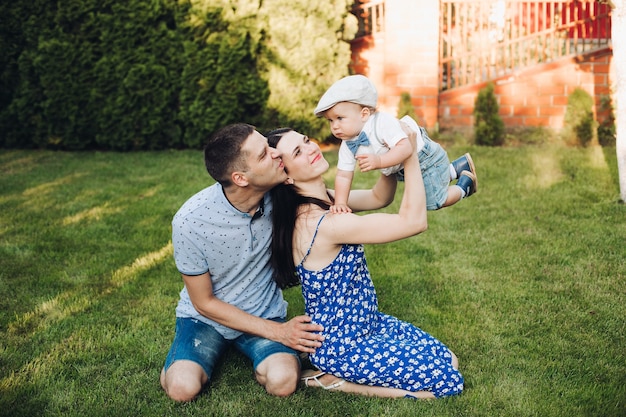 Foto de alegre mãe caucasiana, pai e filho se divertindo juntos e sorrindo no jardim