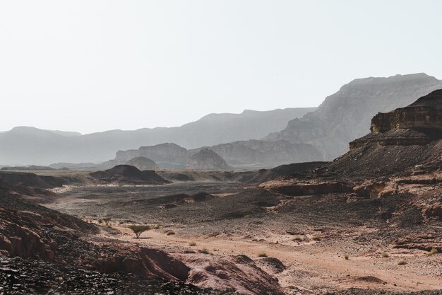 Foto de alto ângulo das colinas em um deserto cercado por montanhas magníficas