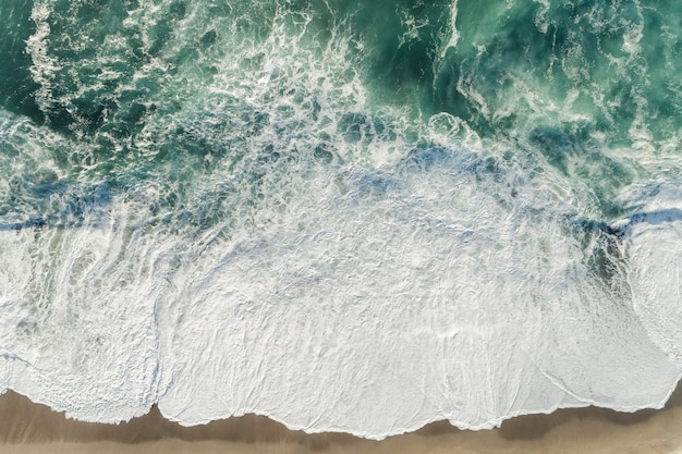 Foto de alto ângulo das ondas do oceano azul espirrando na costa