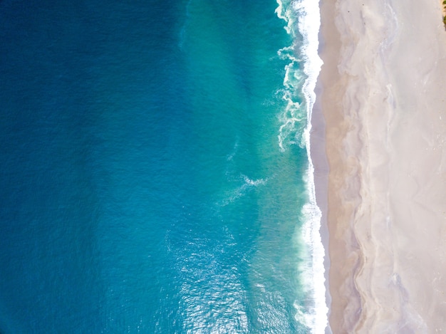 Foto de alto ângulo das ondas do oceano encontrando a costa