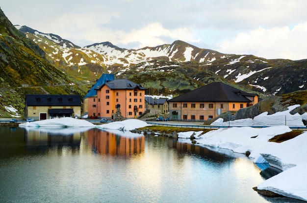 Foto de alto ângulo de algumas casas perto de um lago perto das montanhas cobertas de neve