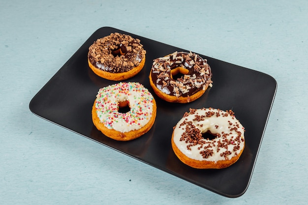 Foto de alto ângulo de deliciosos donuts glaceados com granulado em uma bandeja sobre a mesa