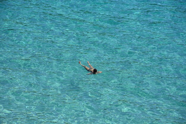 Foto de alto ângulo de um homem tomando banho de sol na água