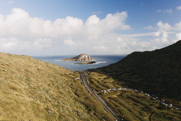 Foto de alto ângulo de um vale de montanha com uma pequena ilha em mar aberto