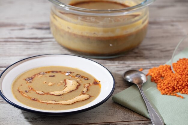 Foto de alto ângulo de uma panela, uma tigela de sopa e uma colher em uma superfície de madeira