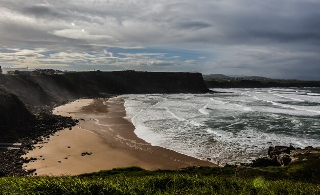 Foto de alto ângulo de uma praia rochosa cercada por falésias sob um céu nublado