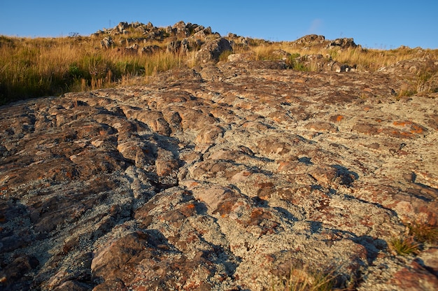 Foto grátis foto de alto ângulo de uma superfície de rocha com belas paisagens do pôr do sol em um céu azul claro