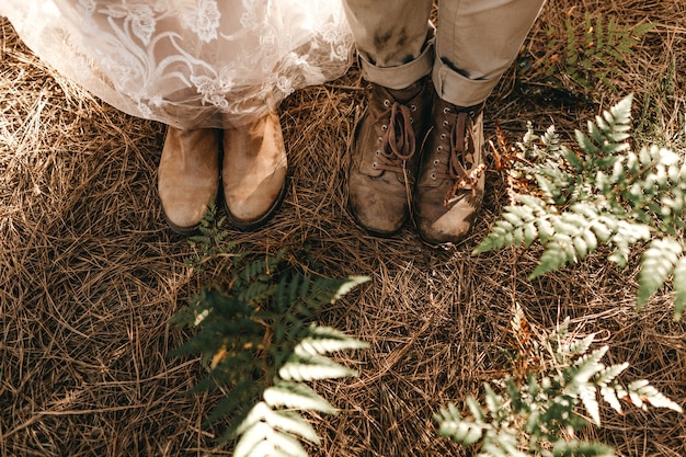 Foto grátis foto de alto ângulo dos sapatos velhos da noiva e do noivo em pé na grama seca