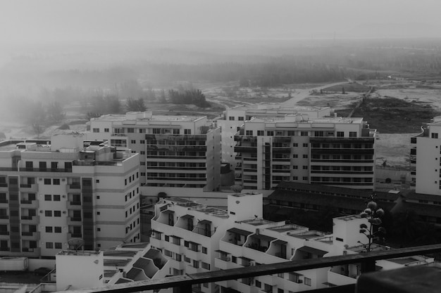 Foto grátis foto de alto ângulo em tons de cinza dos edifícios na praia, capturada no pôr do sol com neblina