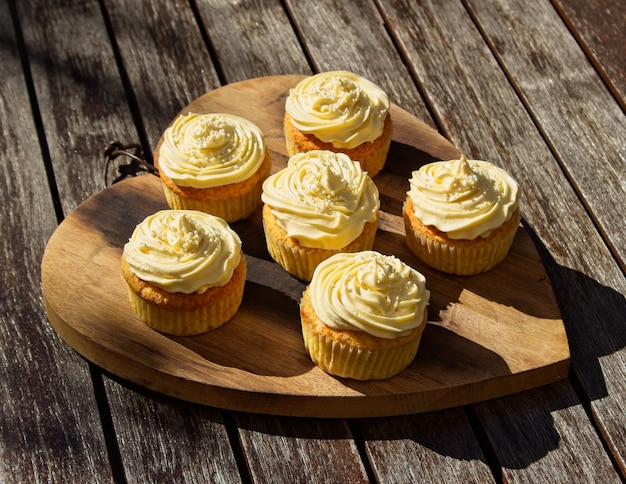 Foto de ângulo alto de deliciosos cupcakes de creme de manteiga doce em uma superfície de madeira