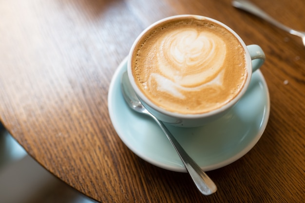 Foto de ângulo alto de uma xícara de cappuccino em uma superfície de madeira