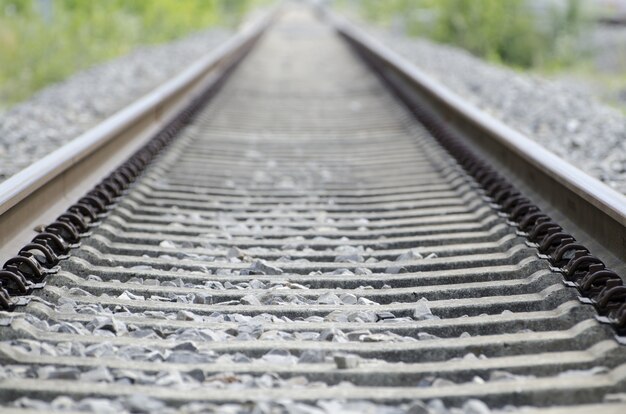 Foto de ângulo alto dos trilhos ferroviários antigos e enferrujados, cobertos por pequenas pedras