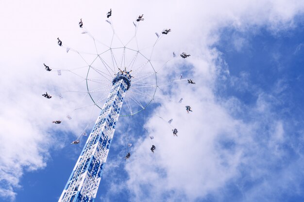 Foto de baixo ângulo de um carrossel circular girando sob um céu cheio de nuvens