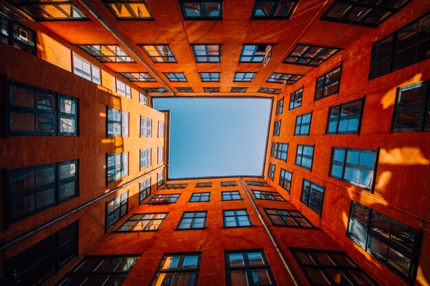 Foto de baixo ângulo de um edifício laranja alto e único tocando o céu