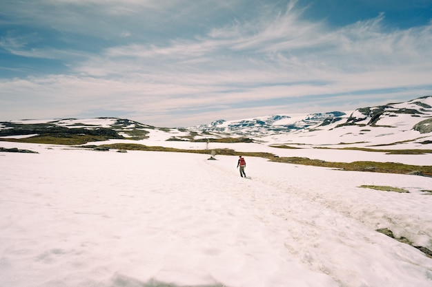 Foto de baixo ângulo de um homem caminhando em colinas nevadas