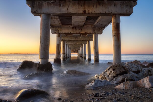 Foto de baixo ângulo de um píer em Marbella, Espanha, durante o nascer do sol