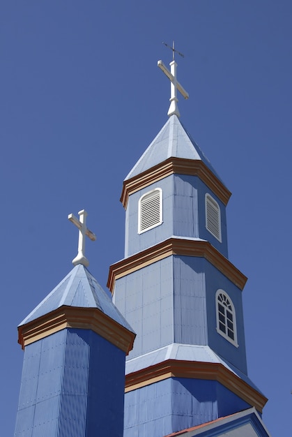 Foto de baixo ângulo de uma pequena igreja azul sob um céu azul e claro