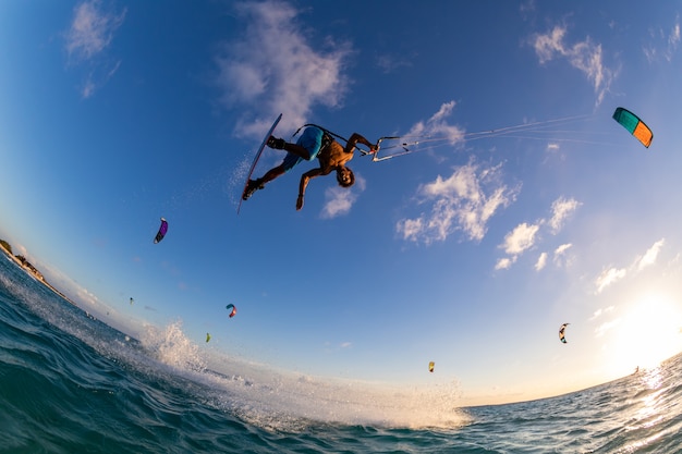 Foto de baixo ângulo de uma pessoa surfando e voando de paraquedas ao mesmo tempo no Kitesurf