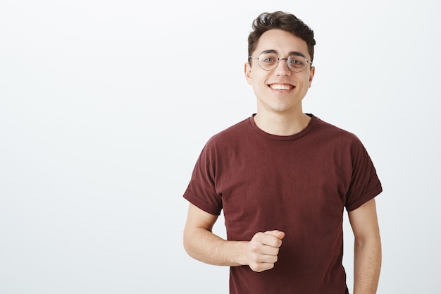 Foto de cintura de um estudante europeu despreocupado e feliz usando óculos redondos da moda e camiseta vermelha