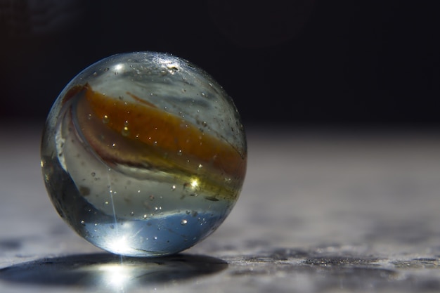 Foto de close de foco seletivo de uma esfera de vidro colorida coberta de gotas de água