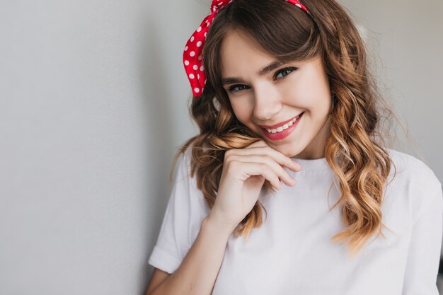 Foto de close-up de inspirada jovem europeia posando com um sorriso. Garota emocionante e emocionante com um penteado ondulado rindo